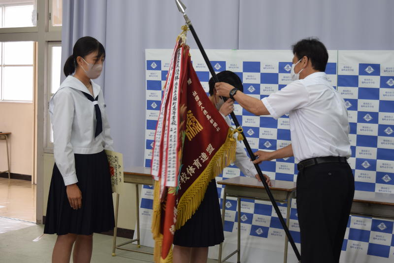 女子ソフトテニス部が県で優勝して優勝旗を授与されています。